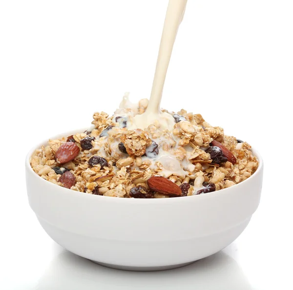 Pouring milk into a bowl with granola cereal — Stock Photo, Image