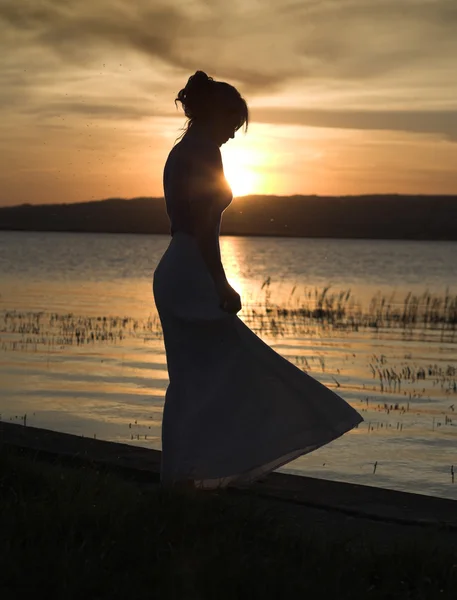 Fiatal, karcsú hölgy táncok egyedül a strandon, naplemente — Stock Fotó