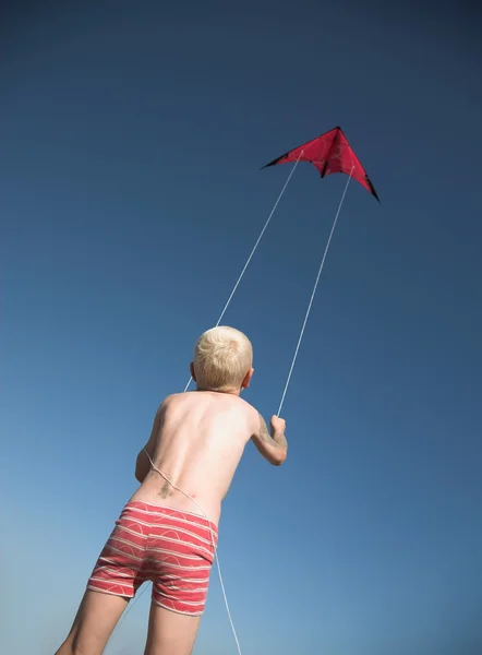 Young blonde boy plays with red kite — Stock Photo, Image