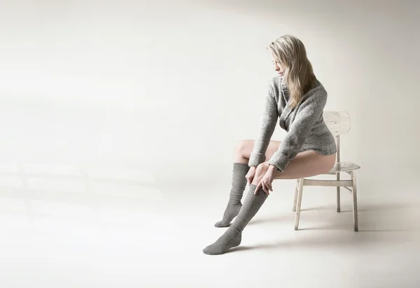 Mooie blonde vrouw trekt haar grijze sokken — Stockfoto