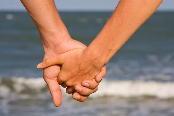 Couple of hands against the sea — Stock Photo, Image