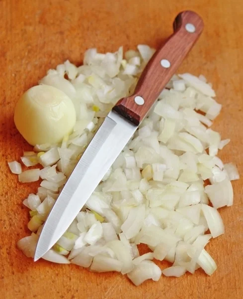 Нарізана цибуля з ножем на дошці — стокове фото