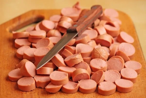 Salchicha cortada en una tabla de cortar con un cuchillo — Foto de Stock