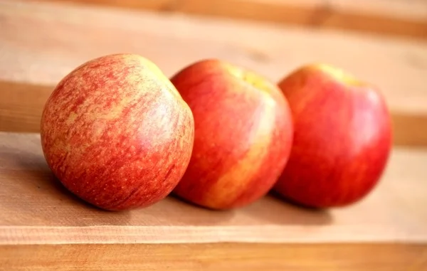 Three fresh red apples on the board — Stock Photo, Image