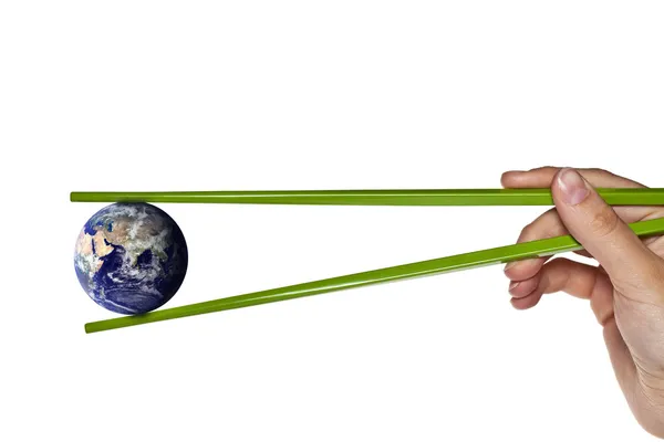 Blue planet earth between green chopsticks — Stock Photo, Image