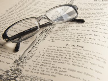 Glasses on the thick old book. clipart