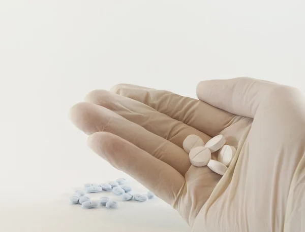 Gloved hand and medicinal pills — Stock Photo, Image
