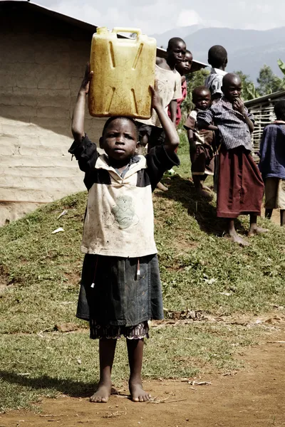 Pequeño niño africano llevando un bidón — Foto de Stock