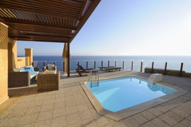 Terrace with a swimming pool in front of the sea clipart