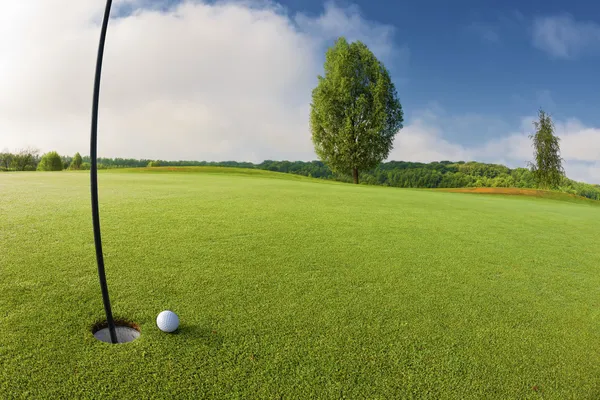 Golf ball near hole on golf course — Stock Photo, Image