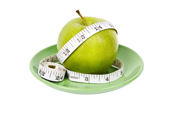 Dieting concept Green apple with measuring tape on green plate — Stock Photo, Image