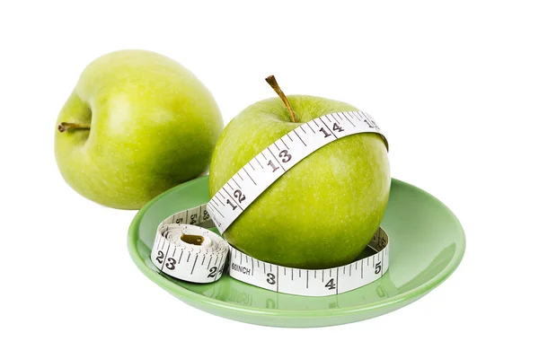 Green apples with measuring tape on green plate — Stock Photo, Image