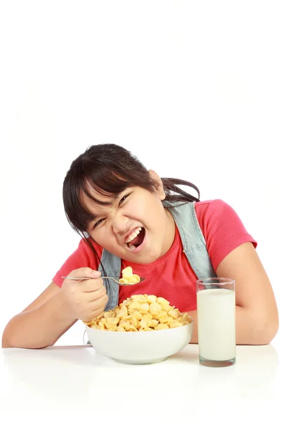 Liten flicka äter frukost med mjölk isolerad på vit — Stockfoto
