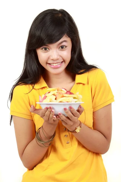 Smiling teenage girl holding a bowl of cut fruits — Stock Photo, Image
