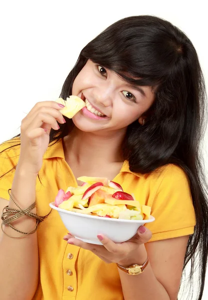 Smiling teenager eating a bowl of cut fruits — Stock Photo, Image