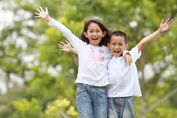 Two kids outdoor raise their hand and smile — Stock Photo, Image