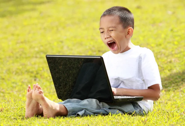 Мальчик зевает, когда играет на ноутбуке — стоковое фото