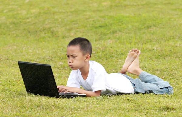 Kleiner Junge mit Laptop im Gras — Stockfoto