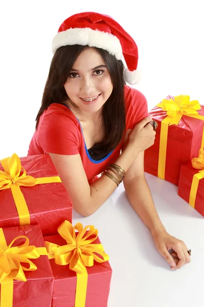 Улыбающаяся девушка в шапке Санты с рождественскими подарками — стоковое фото