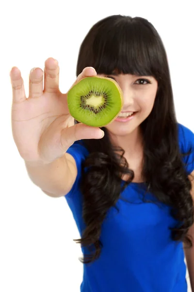 Pretty young woman holds kiwi in front of her eyes — Stock Photo, Image