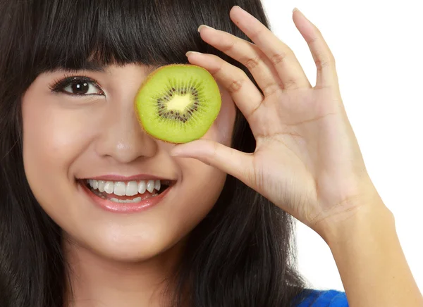 Pretty young woman holds kiwi in front of her eyes. — Stock Photo, Image