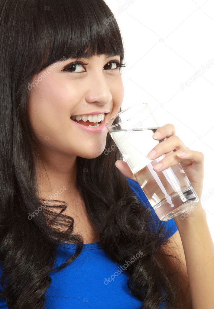 Beautiful young girl drinks water from glass
