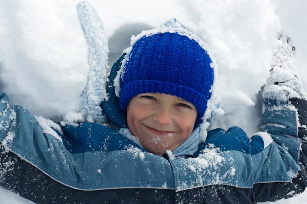 Chlapec ležet ve sněhu Stock Snímky