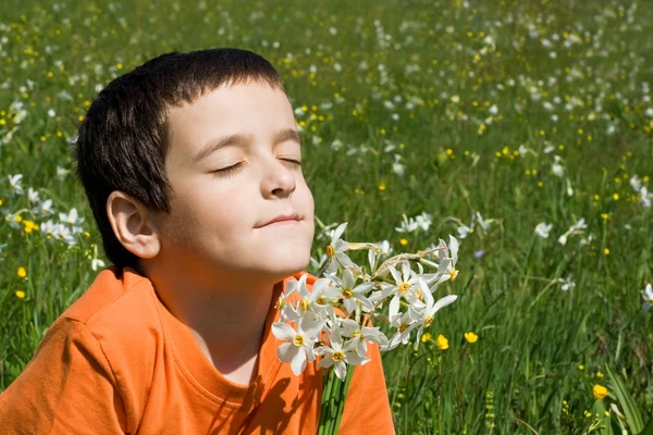 Мальчик, нюхающий цветы — стоковое фото