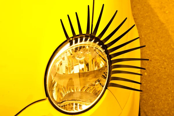 Sarı küçük otomobilinin kirpikleri ile komik lamba. — Stok fotoğraf