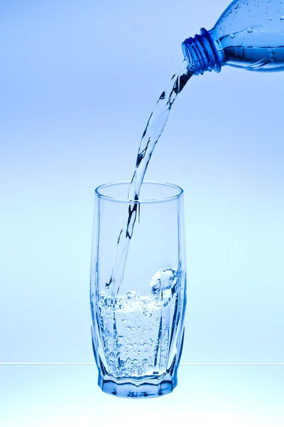 Water flow in a glass from a bottle — Stock Photo, Image