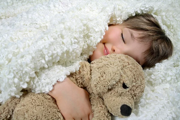 Menina com um cobertor branco e um cachorro de brinquedo macio — Fotografia de Stock