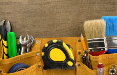 Tools in construction belt on wooden background