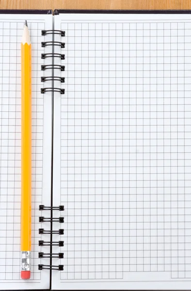 Potlood op gecontroleerde notebook op hout — Stockfoto