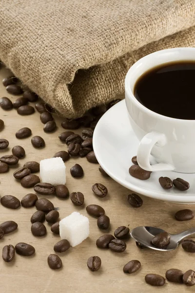 Tasse Kaffee und Bohnen beim Säcken — Stockfoto