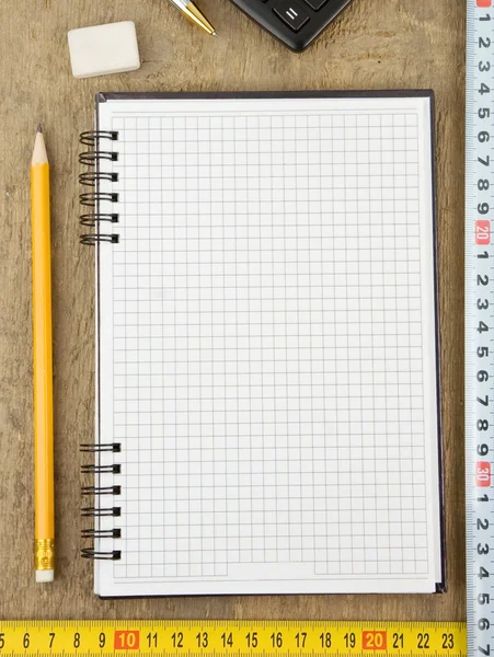 Checked notebook and tepe measure on wood — Stock Photo, Image