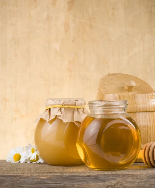 Frasco de vidro cheio de mel e pau — Fotografia de Stock