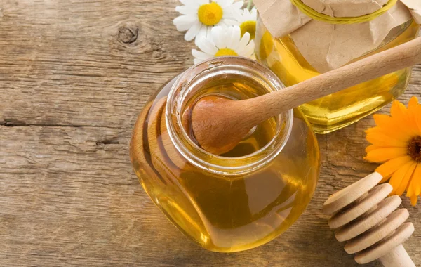 Frasco de mel e flores em madeira — Fotografia de Stock