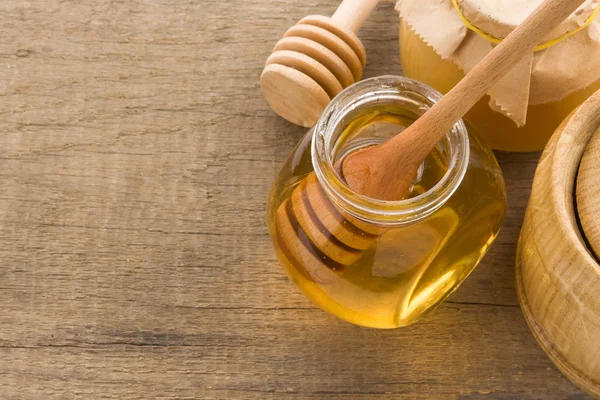 Vaso di vetro pieno di miele e bastone — Foto Stock