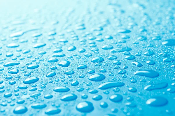 Primer plano de las gotas de agua dulce en la superficie azul — Foto de Stock