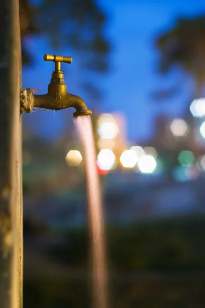 Long exposure night shot of flowing water from old rusty tap — Stock Photo, Image