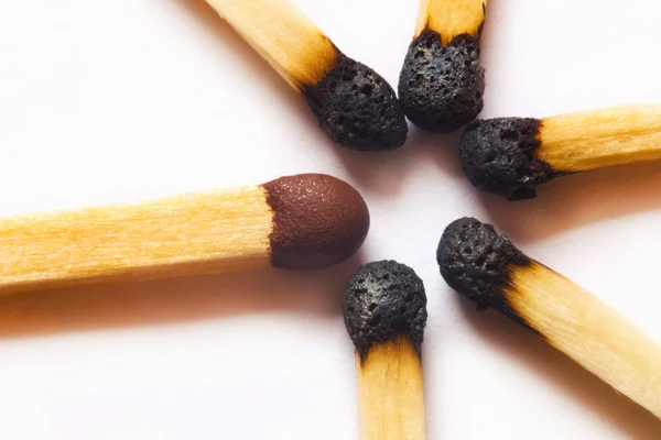 Single match standing out against burned matches — Stock Photo, Image