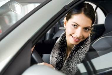 Portrait of vivid brunette looking with interest through the window of her car clipart