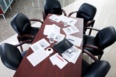 Empty boardroom: black chairs around table with business objects on it clipart