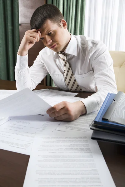 Portrait of smart businessman looking through papers at workplace — Stock Photo, Image