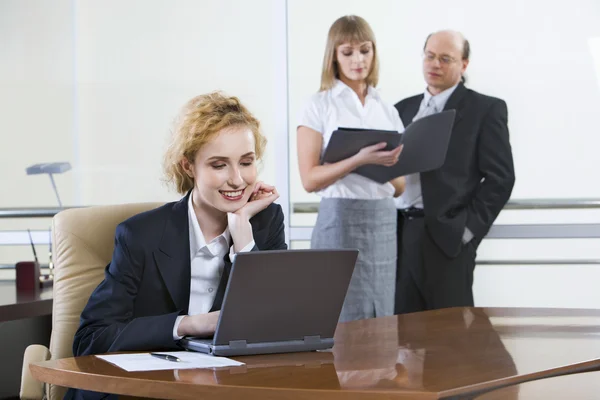 Porträtt av säker affärskvinna som sitter på arbetsplats nära laptop i arbetsmiljön — Stockfoto