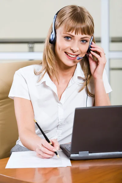 A fiatal üzleti nő ül az fülhallgató-on-a laptop — Stock Fotó