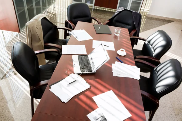 stock image Empty boardroom: black chairs around table with business objects on it