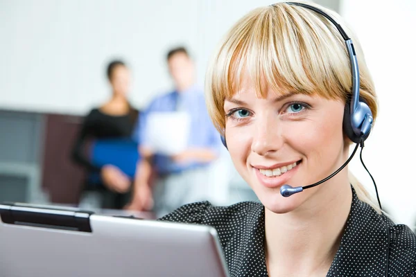 Portrait of friendly smiling telephone operator in a working environment — Stock Photo, Image