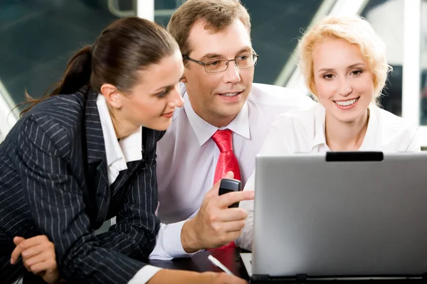 A végrehajtó partnerek látszó-on laptop kijelző irodájában dolgozva portré — Stock Fotó
