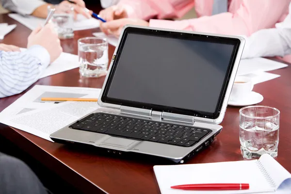 Imagen de la computadora portátil en el lugar de trabajo con asociados hablando en segundo plano — Foto de Stock